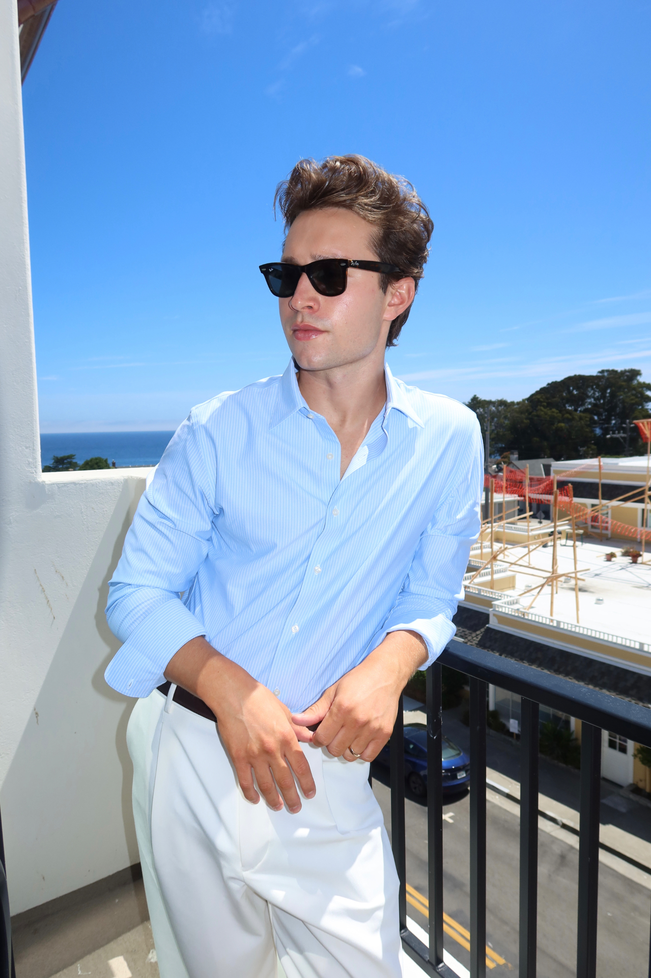 Griffin in a blue shirt and white trousers on a coastal balcony